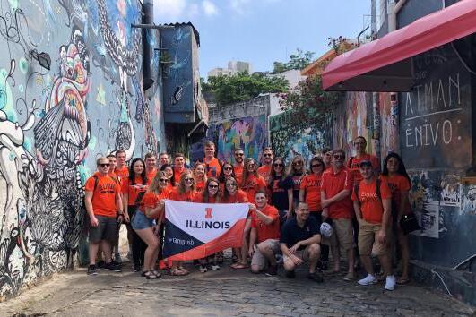 Study abroad students holding an Illinois sign in batman alley