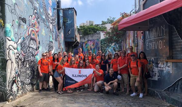 Study abroad students holding an Illinois sign in batman alley