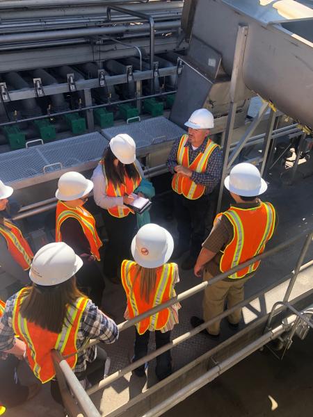 Students on a tour of the processing facility with hard hats and vests on