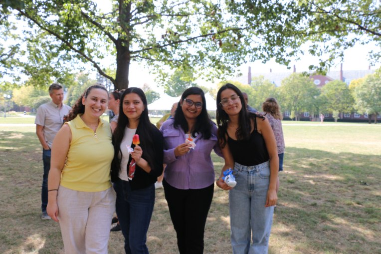 four females stand outside and pose for a photo while holding frozen treats