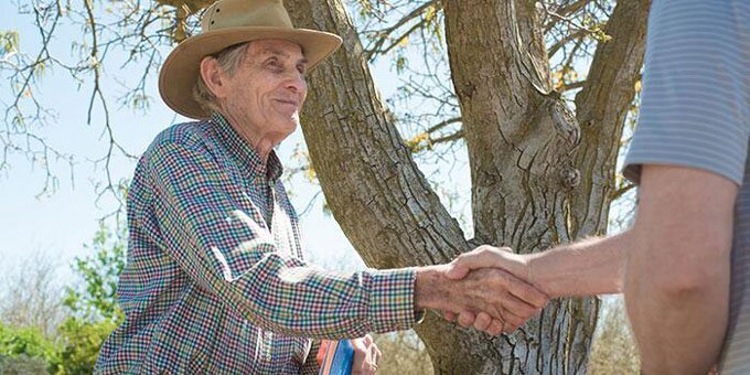 Two people shaking hands in front of a tree