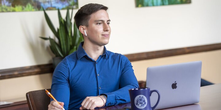 Student sitting at a desk working on a computer and taking notes