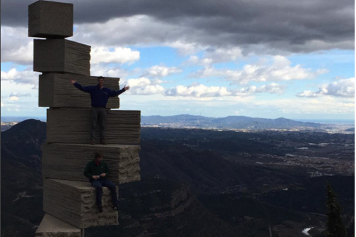 Two students standing on a stair-like structure outlooking mountains