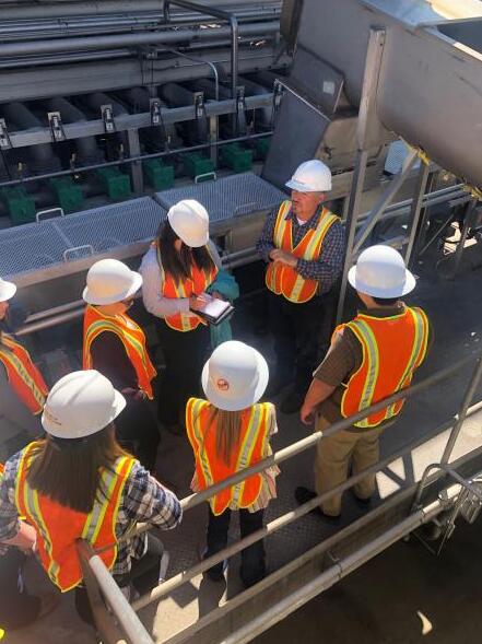 Students on a tour of the processing facility with hard hats and vests on